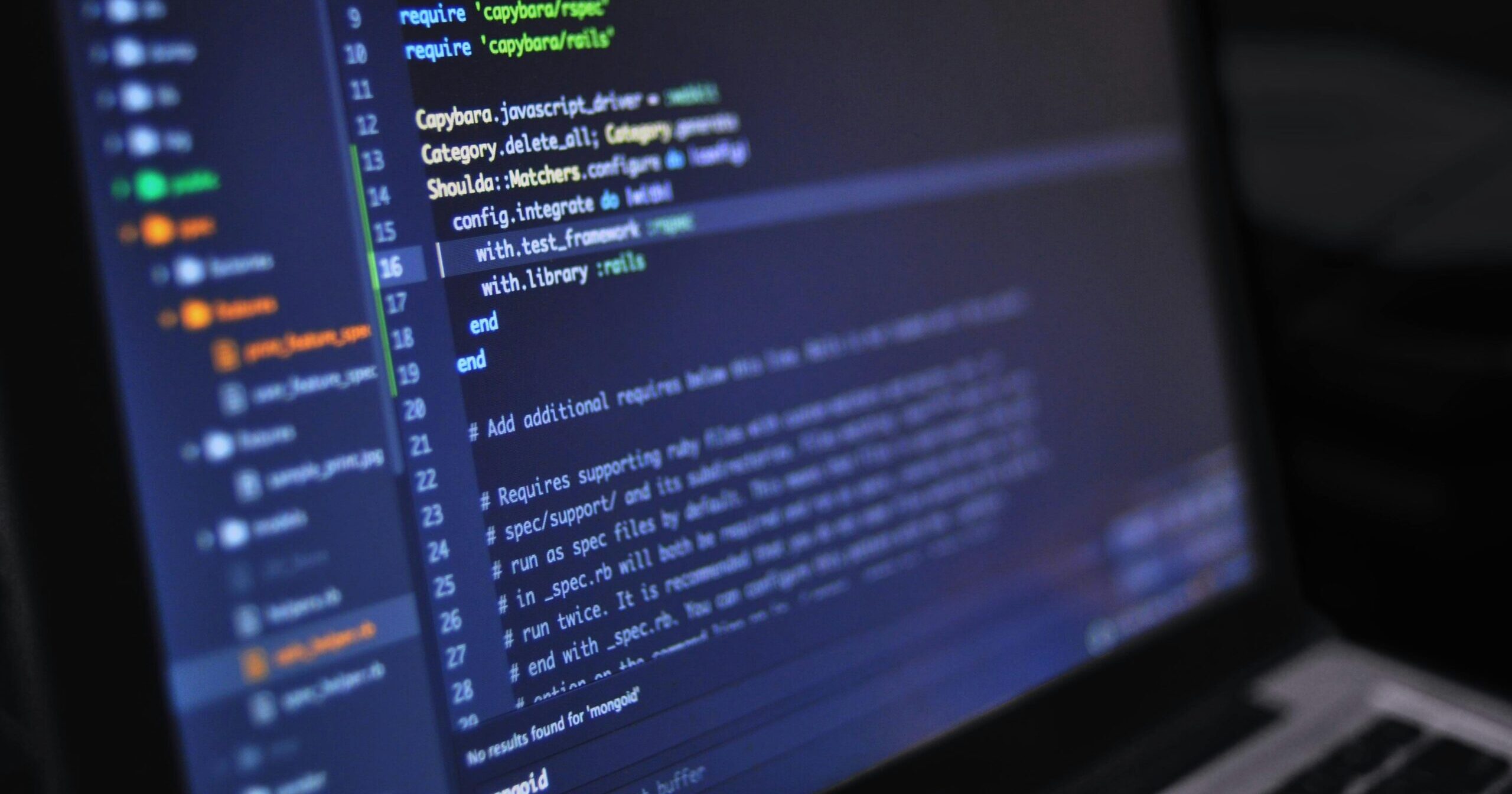 Close-up of a computer screen displaying programming code in a dark environment.